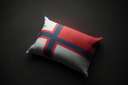 Red-lit rectangle cushion with the Norwegian flag on a black backgroundの素材