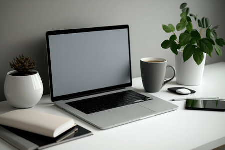 Laptop with blank display, coffee, houseplant, and stationery on grey tableの素材