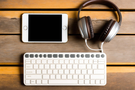 Top view of a keyboard, headphones and smartphone with empty blank screen on a background wooden table, blank for your text or content or design, closeup, free space. Mock up top viewの素材