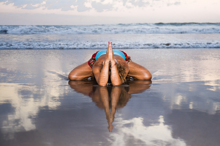 young fit and attractive sport woman in beach sunset yoga practice workout sitting on wet sun in front of the sea in meditation and relaxation exercise in mind and body care and healthy lifestyleの写真素材