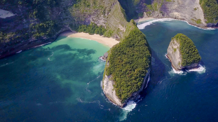 amazing aerial view from above of Asian island coastline with turquoise color sea water waves and foam and white sand tropical paradise beach next to rock cliff in holidays travel destination conceptの写真素材