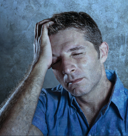 close up portrait of young attractive man with hand on his face in stress suffering headache feeling...