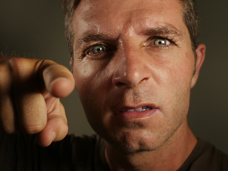 close up portrait of young angry and upset man pointing with finger as if scolding and blaming you...
