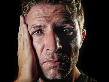 close up portrait of sad and depressed man with hand on face looking desperate feeling frustrated and helpless in depression and sadness facial expression concept isolated black bgの写真素材