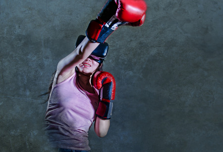 portrait of young woman with boxing gloves playing video game using VR virtual reality goggles simulating boxer fighting 3 dimension illusion combat in gaming and technology device conceptの写真素材