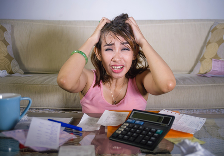 young attractive stressed and worried hispanic woman pulling her hair suffering stress banking and calculating monthly expenses debt in domestic accounting stress and financial problem の写真素材