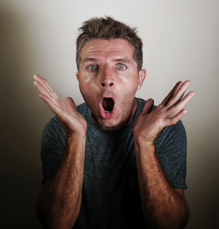 portrait of young attractive and surprised man gesturing in shock and disbelief overacting in shocked hands gesture on isolated background in surprise emotion and face expression conceptの写真素材