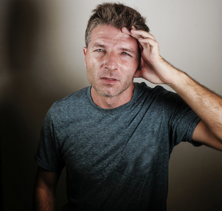 portrait of young attractive sad and depressed man looking tired and exhausted suffering stress and depression on isolated background in worried face expression and upset emotion conceptの写真素材