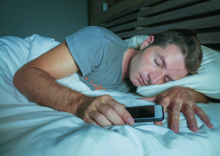 young attractive and handsome tired man on his 30s or 40s in bed sleeping peacefully and relaxed at...
