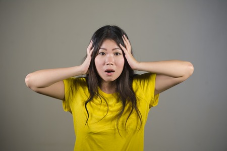young sweet and beautiful Asian Korean woman gesturing shocked and surprised as if oh my god what a disaster in astonished face expression on isolated background in surprise emotionの写真素材