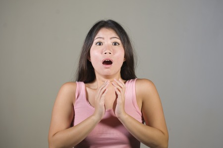 young sweet and beautiful Asian Korean woman gesturing shocked and surprised as if oh my god what a...