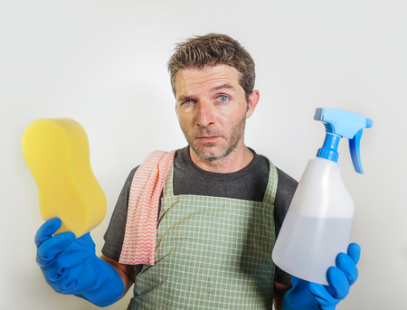 isolated sad and tired man in domestic cleaning stress holding sponge and detergent soap spray...
