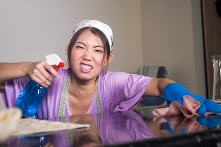 young pretty overworked and sad Asian Chinese service maid woman working domestic cleaning and washing home kitchen angry upset and frustrated in housework and housekeeping stressの写真素材