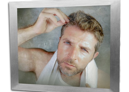 lifestyle portrait of attractive worried and concerned Caucasian man looking at bathroom mirror...