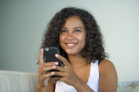 lifestyle isolated portrait of young happy and beautiful latin woman at home using mobile phone...