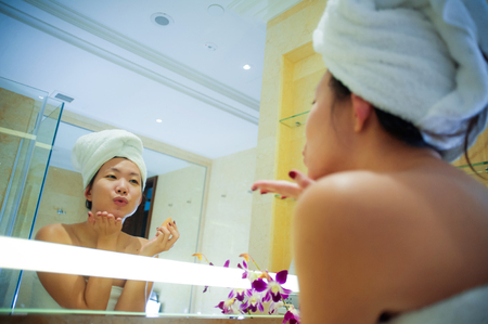 lifestyle fresh portrait of young happy and beautiful Asian Korean woman at home or hotel bathroom...