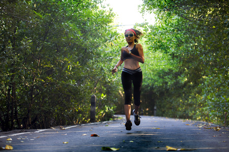 lifestyle outdoors portrait of young attractive and fit woman with hairband training hard on asphalt road running workout at beautiful trees city park in exercise fitness and health care conceptの写真素材