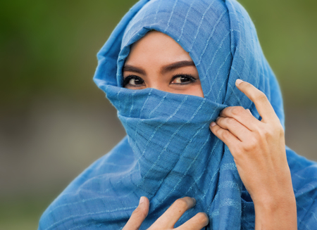 lifestyle isolated portrait of young beautiful and happy Asian woman smiling covered by muslim hijab head scarf in islamic culture and religion conceptの写真素材