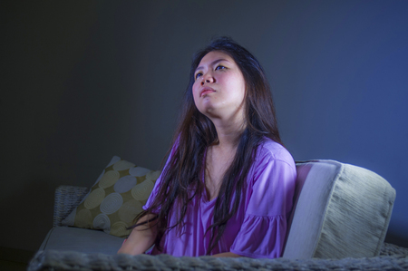 young sad and depressed Asian Chinese woman at home sofa couch crying desperate and helpless suffering anxiety and depression feeling pain in relationship and lonely life problem conceptの写真素材