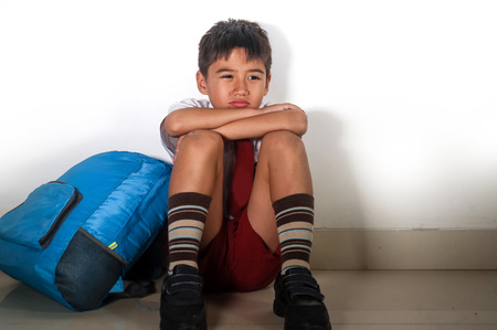 lifestyle dramatic bullying victim portrait of young sad scared kid 8 years old in school uniform...