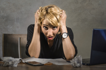 young attractive and desperate business woman working with laptop computer sitting at office desk screaming sick and overwhelmed suffering job stress feeling frustrated and anxiousの写真素材