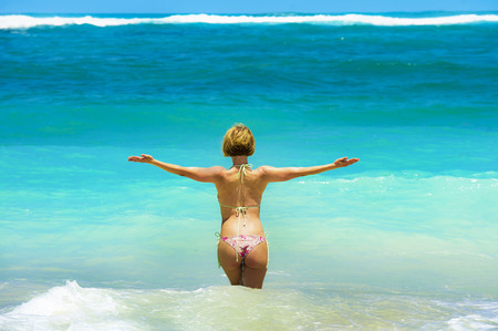 back portrait of young attractive woman in bikini looking at horizon at beautiful desert beach enjoying Summer holidays travel destination in relaxing tropical paradise with turquoise sea backgroundの写真素材
