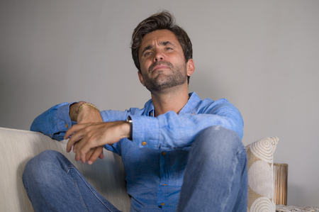 lifestyle portrait of young attractive and handsome sad latin man sitting tired and depressed at...
