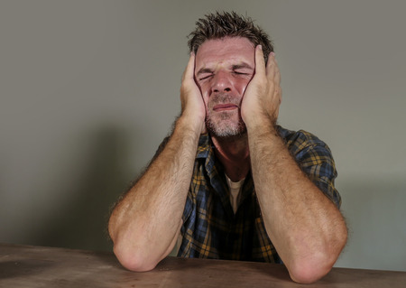 dramatic portrait of young sad and depressed man feeling anxious and overwhelmed crying desperate suffering depression problem and anxiety crisis isolated on grey backgroundの写真素材