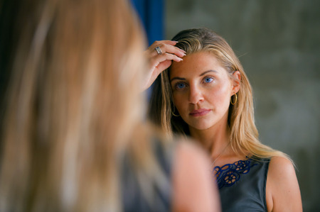 young beautiful and happy blond woman enjoying shopping trying out clothes in the mirror at vintage...