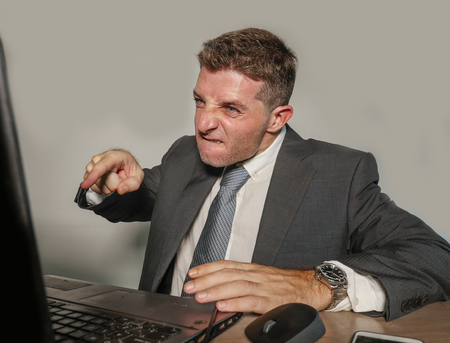 young stressed and overwhelmed businessman in suit and tie working angry at office laptop computer...