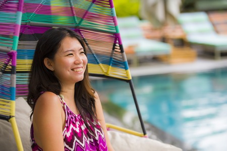 young beautiful and happy Asian Chinese tourist woman relaxing at tropical luxury resort swimming...