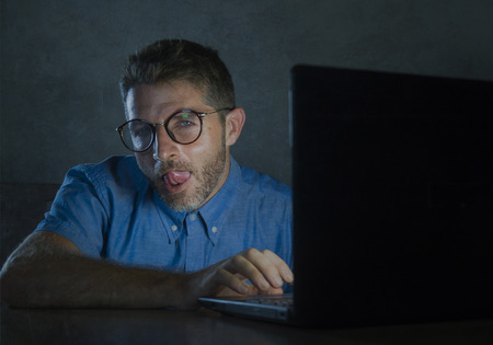 young lascivious and aroused porn addict man in nerd glasses watching sex movie online late night at...