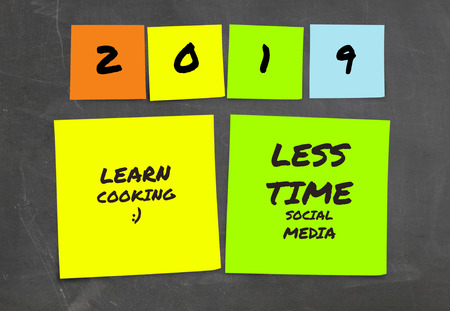 list of handwritten 2019 New Year resolutions and goals in sticky notes in commitment determination and positive thinking concept isolated on blackboard backgroundの写真素材