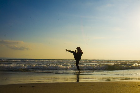 silhouette of young fit and aggressive Muslim woman covered in Islam hijab head scarf training...