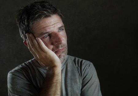 isolated dark background portrait of 30s to 40s sad and depressed man looking thoughtful and worried...