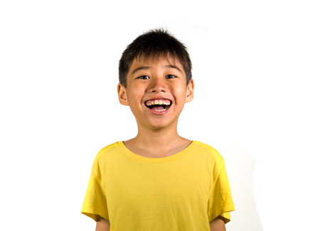 portrait of young happy and excited child smiling and laughing cheerful wearing yellow t-shirt isolated on white background in kid happiness and joyful face expression conceptの写真素材