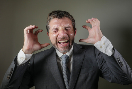 desperate and stressed businessman screaming crazy frustrated and worried suffering depression problem and anxiety crisis isolated on grey background in corporate company failure job and stressの写真素材