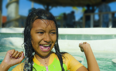 lifestyle candid portrait of pretty excited and happy child in cute girl swimsuit smiling cheerful splashing water in swimming pool enjoying Summer holidays at tropical resortの写真素材