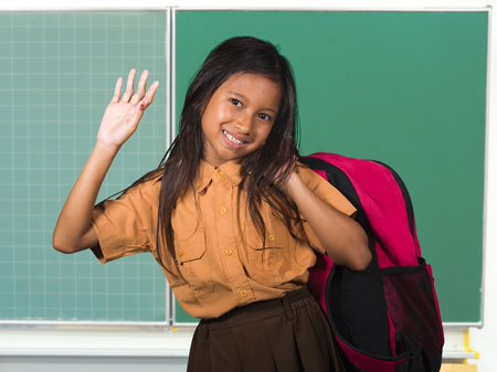 portrait of beautiful happy and excited female child in school uniform carrying student bag smiling...