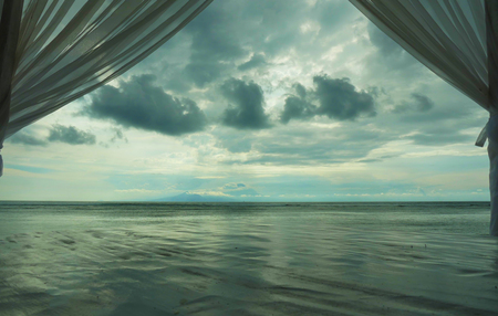 beautiful view of tropical beach at Gili island beach of Lombok in Indonesia in Asia through luxury resort window room with curtains in summer holidays travel and tourist destination concept
の写真素材