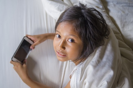 lifestyle portrait of sweet happy and beautiful 7 years old child having fun playing internet game...