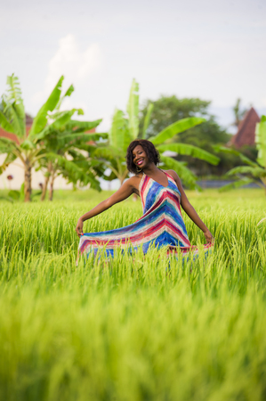 lifestyle portrait of young attractive and happy black African American woman posing cheerful having fun outdoors at beautiful rice field background enjoying holidays trip in nature and tourism conceptの写真素材