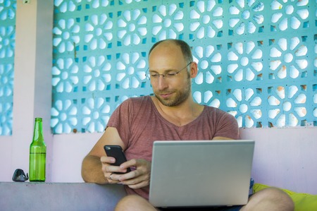 lifestyle portrait of young happy and confident backpacker man working with laptop computer and...