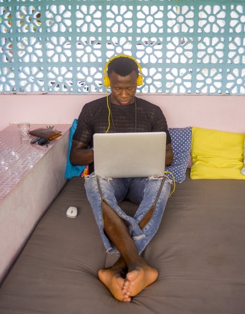 young attractive and hipster black African American business man networking with laptop computer and...