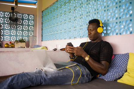 young handsome and cool black afro American hipster man with headphones networking relaxed with...