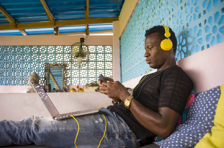 young handsome and cool black African American hipster man with headphones networking relaxed with...