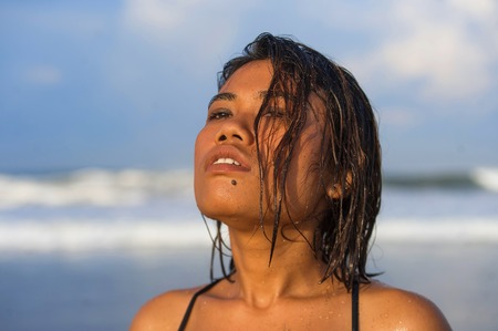 head and shoulders lifestyle portrait of young beautiful and sexy Asian girl in bikini with wet hair enjoying holidays at tropical beach posing cool relaxed and happy at the sea in exotic beauty conceptの写真素材