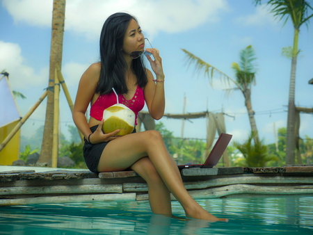 young beautiful and happy Asian Indonesian teenager woman in bikini at tropical resort swimming pool...