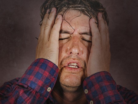 close up dramatic portrait of stressed and overwhelmed man holding head with hands in crazy stress...