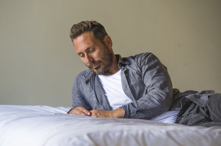 interior portrait of 30s to 40s happy and handsome man at home in casual shirt and jeans lying on...